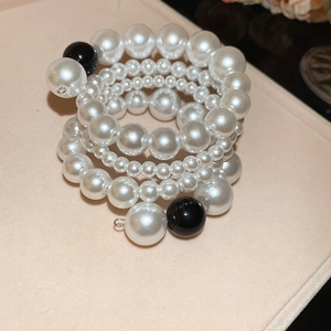 Detail shot of multilayered twisted pearl bracelet with white and black round beads