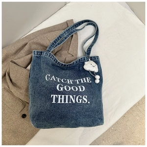 Détail du cabas en denim bleu avec Catch the Good Things texte et pendentif nuage