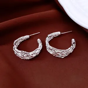 Boucles d'oreilles créoles C en argent torsadé sur un tissu en velours rouge