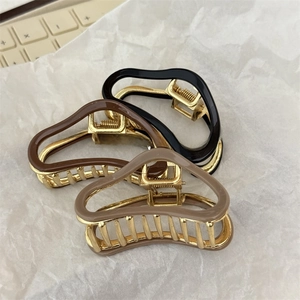 Detailed top view of three vintage-style metal hair claws in black, brown and khaki colors