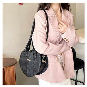 Détail d'un sac à main noir en forme de cœur avec texture crocodile et bijoux dorés