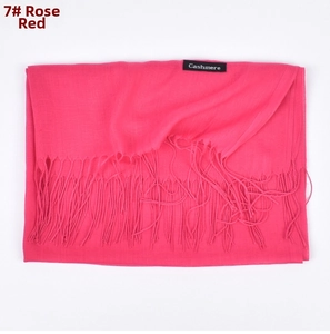 Detail view of rose red cashmere scarf with soft fringe edges and fabric label