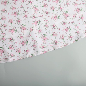 Dettaglio del tessuto floreale con cuciture pulite e piccoli fiori rosa su bianco