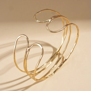 Detailed view of layered wavy gold cuff bracelet with polished finish and open design