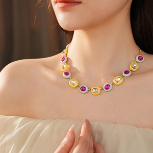 Detail of vintage luxury necklace featuring pink and yellow enamel with rose red gemstones