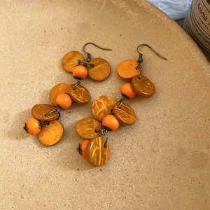 Gros plan de perles en bois orange et glands en noix de coco sur crochets en bronze