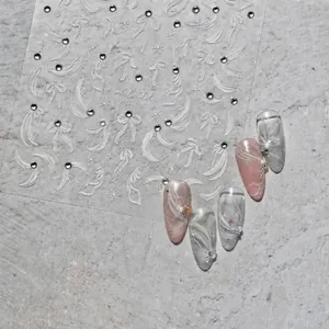 Detalle de pegatinas 5D para uñas con lazos blancos y diamantes de imitación brillantes