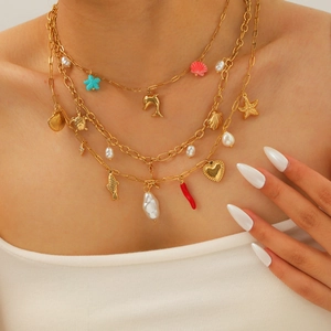 Layered gold necklace featuring seahorse shells and pearls on female model