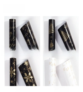Detail of four black and white Christmas gift wrap rolls with premium gold foil patterns