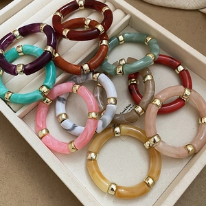 Detail of colorful acrylic tube bracelets with gold spacers and marble texture