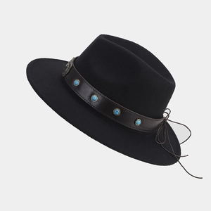 Detalle del sombrero fedora negro con banda de cuero marrón y cuentas de piedra azul