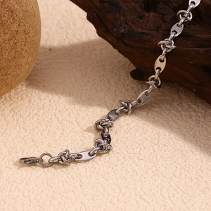 Macro detail of silver-colored coffee bean link chain and clasp on rustic stone background