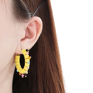 Gros plan de créoles bohèmes jaune vif avec perles colorées portées par un mannequin