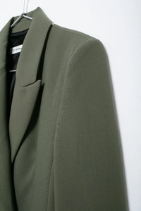 Vue macro détaillée de l'épaule, du revers et de la texture du tissu du blazer vert