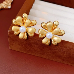 Macro shot of 18k gold plated flower stud earrings with a white pearl center detail