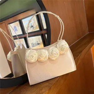 Detail of cream satin evening bag featuring pearl handle and 3D fabric rose flowers