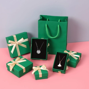 Macro view of dark green jewelry gift boxes with gold ribbons and matching carry bags