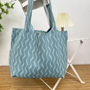 Close-up of blue wavy pattern knit tote bag showing thick fabric texture and wide handle