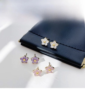 Detail of floral stud earrings with sparkling crystals in clear purple and pink colors