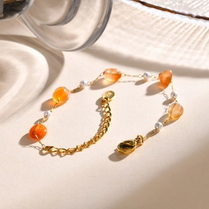 Detailed close-up of gold-plated chain with orange amber-style beads and white pearls