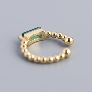 925 silver ear cuff with gold beads and emerald green zircon in a professional studio shot