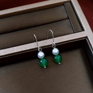Detail of vintage drop earrings featuring white pearls and green agate beads in a jewelry box