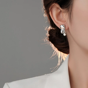 Close-up of minimalist silver irregular metal stud earring with a white pearl on ear