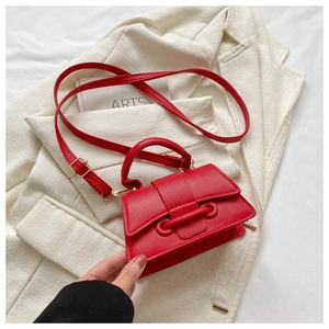 Detail of red textured leather small square bag with gold hardware and top handle