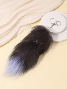 Detail of a fluffy faux fox tail keychain with brown to blue gradient and silver clasp