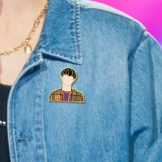 Detail of artistic enamel portrait brooch pinned on a light blue denim jacket lapel