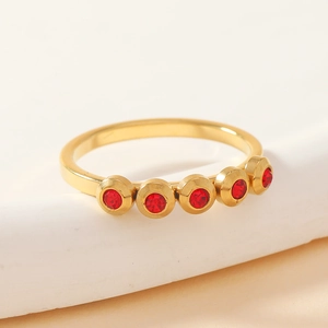 Polished gold titanium steel ring featuring five bezel-set red gemstones in a minimalist style