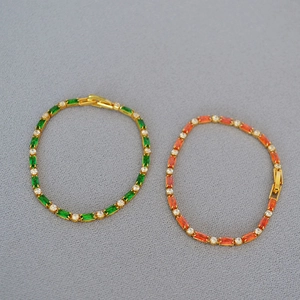 Macro shot of rectangular emerald and orange cubic zirconia in a gold plating setting