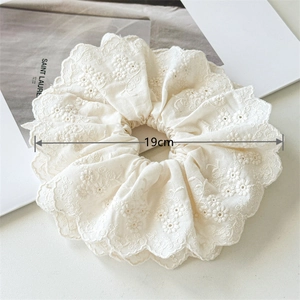Détail d'un chouchou en dentelle de coton crème de 19 cm avec broderie florale élégante