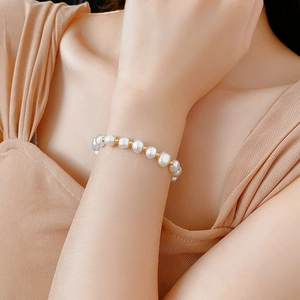 Detailed view of adjustable faux pearl bracelet with gold metal beads on wrist