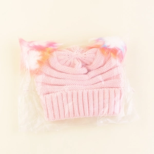 Detailed view of pink knitted baby hat with cat ears and colorful rainbow faux fur pom-poms