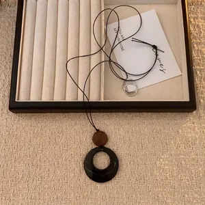 Detail einer Boho-Halskette mit schwarzem Ringanhänger und brauner Holzperle auf Display