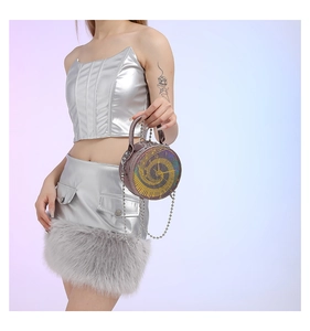 Detail of round brown crossbody bag featuring a unique clock face design and silver chain