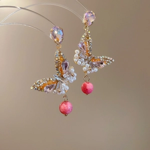 Detailed macro view of French crystal flower earrings with purple rhinestones and pearls