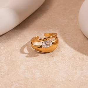 Macro detail of gold open ring with an oval cubic zirconia on a stone surface