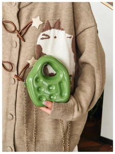 Detail of green jelly bag featuring unique cut-out handle and gold chain shoulder strap
