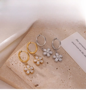 Detailed macro of minimalist flower drop earrings in gold and silver with zircon petals