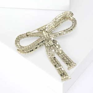 Elegant silver bow brooch with sparkling rhinestones on a minimalist white background