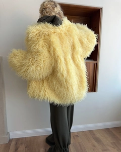 Rear view of long yellow faux fur coat showing oversized silhouette and soft texture