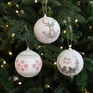 Three white frosted Christmas foam balls with reindeer and snowflake patterns on a tree