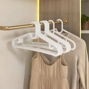 White non-slip plastic clothes hangers on a gold rail for home wardrobe storage