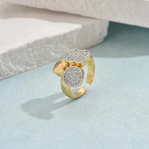 Detail of gold clover ring with micro-pave cubic zirconia on textured background