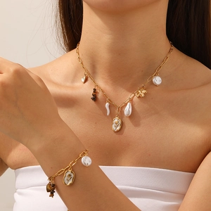Gold paperclip chain jewelry set with white flower pendant and pearl accents on a model