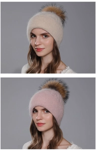 Close-up of knit winter hat with large fur pom-pom in cream white and soft pink