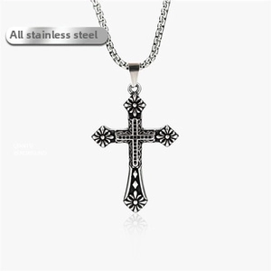Detail of vintage stainless steel cross pendant with sun flower pattern on a steel chain