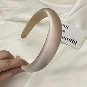 Detail of padded champagne satin headband with high-gloss texture and thick sponge core